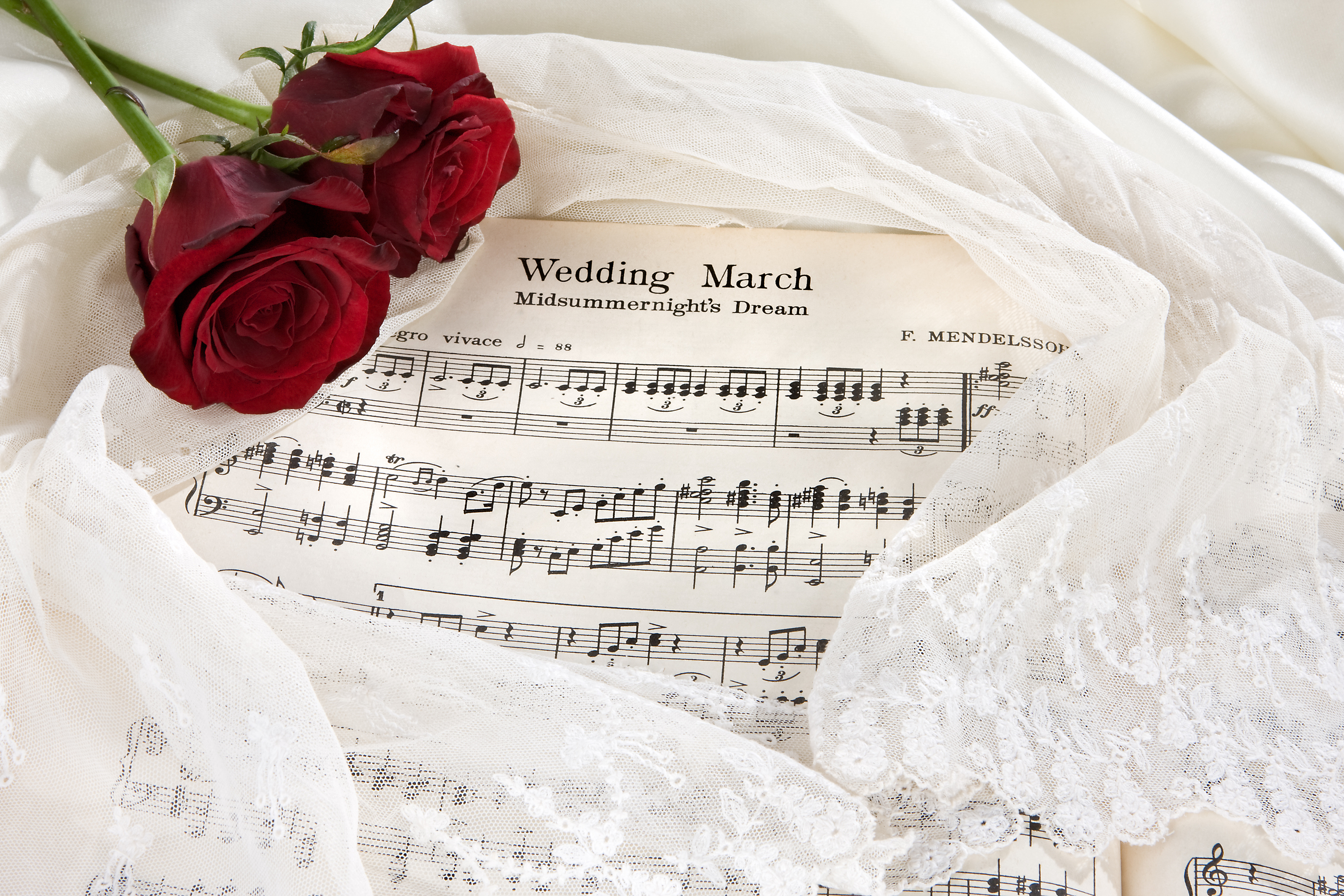 Sheet music of the Wedding March with roses and bridal veil